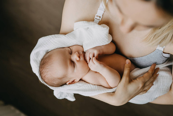 Νεογνό μωρό κοιμάται στην αγκαλιά της μητέρας του. - Φωτογραφία, εικόνα