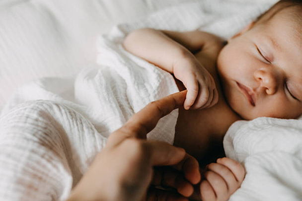 Closeup of a newborn baby holding mother's finger. - Фото, зображення