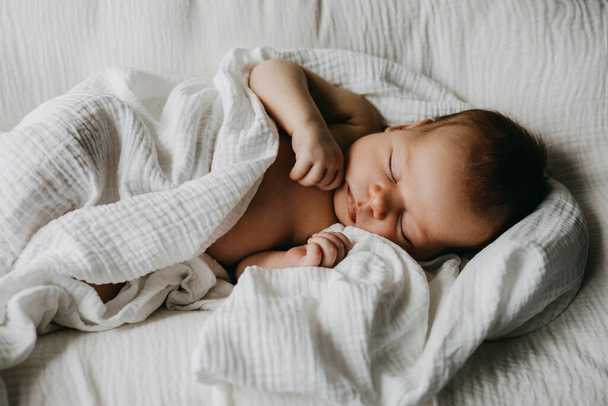 Newborn baby sleeping in a baby nest, covered with white muslin blanket. - Foto, Imagem