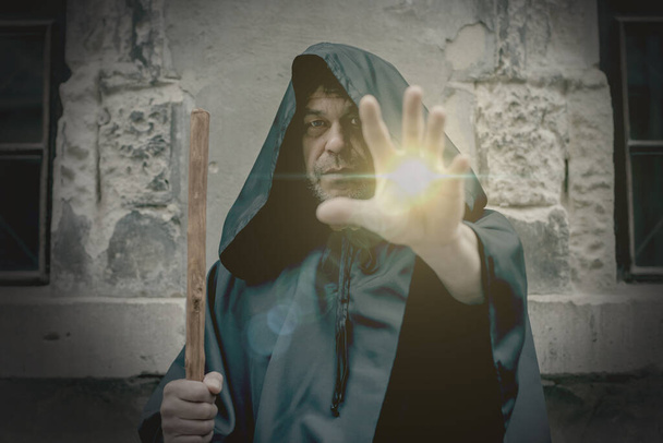 Світло і сила виходить з руки літнього монаха в чорній касочці. Концепція: зцілення і магія, прокляття і благословення
 . - Фото, зображення
