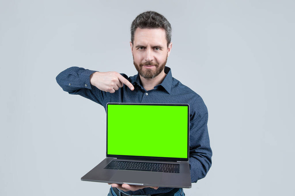 mature man showing green screen. modern wireless laptop. copy space. webinar pc advertisement. - Foto, afbeelding