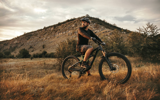 Active man riding electric mountain bike in nature - 写真・画像