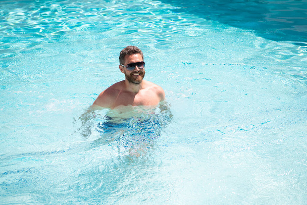 gelukkig bebaarde man in zonnebril genieten ontspannen in spa resort zwembad op zomervakantie, zomer. - Foto, afbeelding