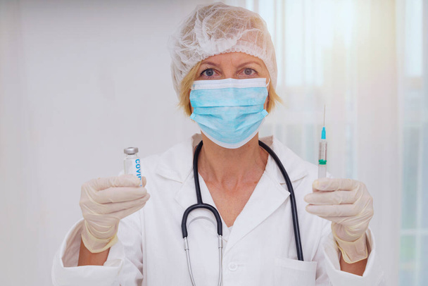 Arzt mit Maske und Spritze ist bereit, den Impfstoff gegen Covid 19 zu verabreichen - Foto, Bild
