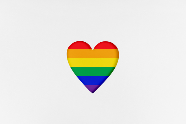 Herzform mit neu gestalteter LGBTQ-Flagge auf weißem Karton. Bedruckter Karton mit gestanzter Herzform. Ansicht von oben - Foto, Bild