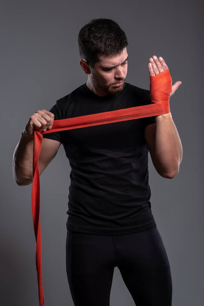 Nuori mies käärimässä käsiään punaisella nyrkkeilyteipillä - Valokuva, kuva