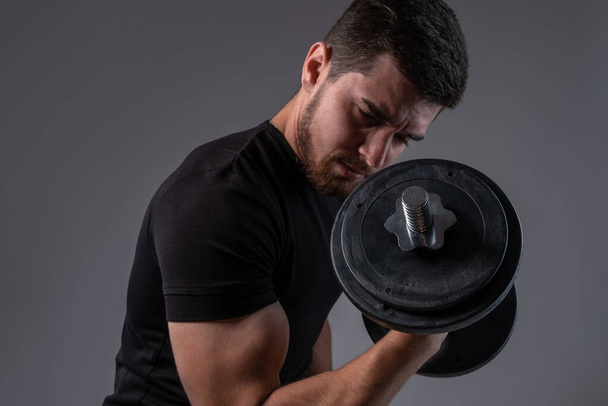 skoncentrowany młody człowiek robi biceps loki z dumbell - Zdjęcie, obraz