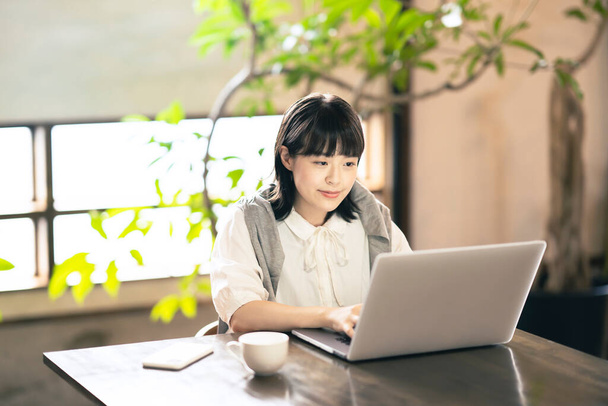 Uma mulher olhando para uma tela de laptop em um ambiente acolhedor - Foto, Imagem