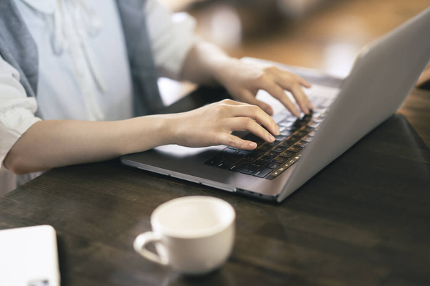 Hände einer jungen Frau, die in einem ruhigen Raum einen Laptop bedient - Foto, Bild