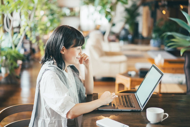 Een vrouw kijkt naar een laptop scherm in een warme sfeer - Foto, afbeelding