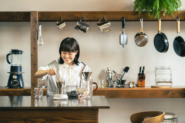 Μια νεαρή γυναίκα που φτιάχνει καφέ σε έναν χαλαρωτικό χώρο - Φωτογραφία, εικόνα