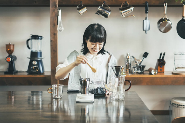 Młoda kobieta parzy kawę w relaksującej przestrzeni - Zdjęcie, obraz