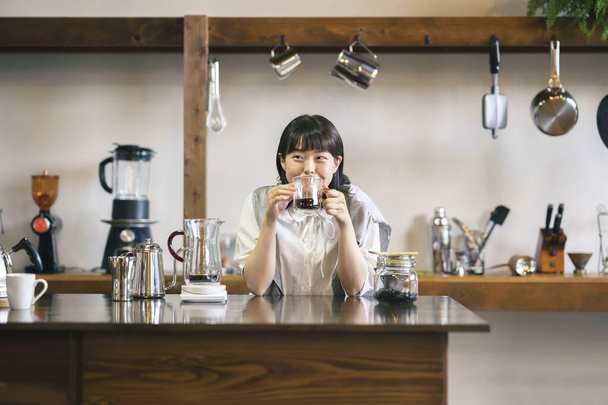 Nuori nainen keittää ja juo kahvia rauhallisessa ilmapiirissä - Valokuva, kuva