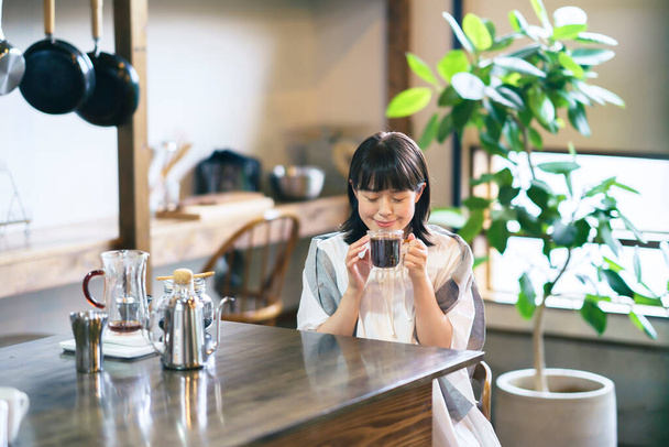 Una giovane donna che prepara e beve caffè in un'atmosfera tranquilla - Foto, immagini