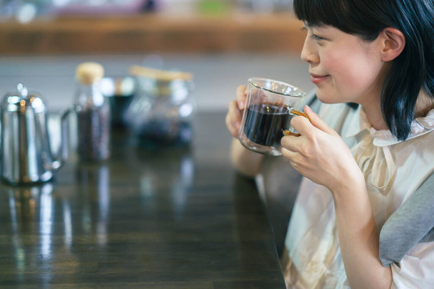 Nuori nainen juo kahvia lämpimässä ilmapiirissä - Valokuva, kuva