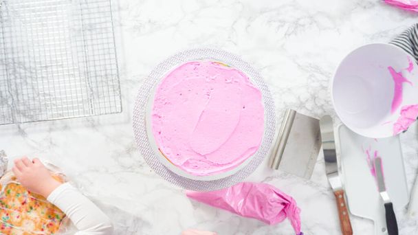 Flat lay. Step by step. Frosting round funfetti cake layers with pink buttercream frosting. - Foto, imagen