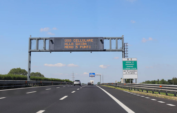 signo de la autopista con la inscripción en italiano, lo que significa que los puntos se deducen de la licencia de conducir si el conductor conduce el coche con un teléfono móvil en idioma italiano - Foto, Imagen