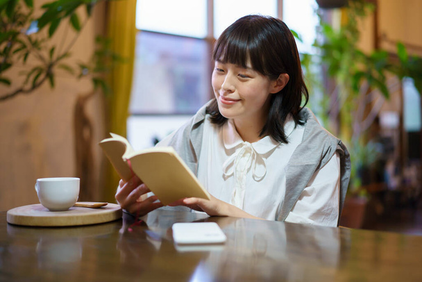 A young woman reading a book in a warm atmosphere - Photo, Image