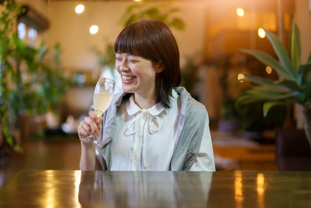 Een jonge vrouw met een glas champagne in een warme sfeer - Foto, afbeelding