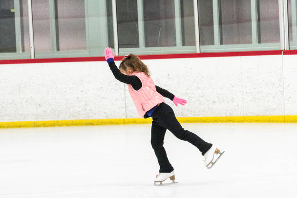 Pequeña patinadora practicando sus elementos en la práctica de patinaje artístico matutino. - Foto, imagen