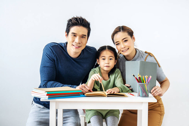 Retrato desfrutar feliz sorrindo amor asiático família pai e mãe ajudando pequena filha fazer lição de casa em casa na sala de estudo, conceito de educação - Foto, Imagem