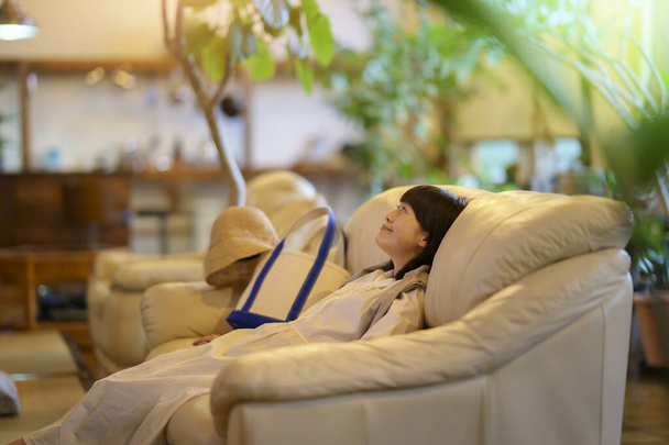 Молода жінка заспокоюється на дивані ввечері
 - Фото, зображення