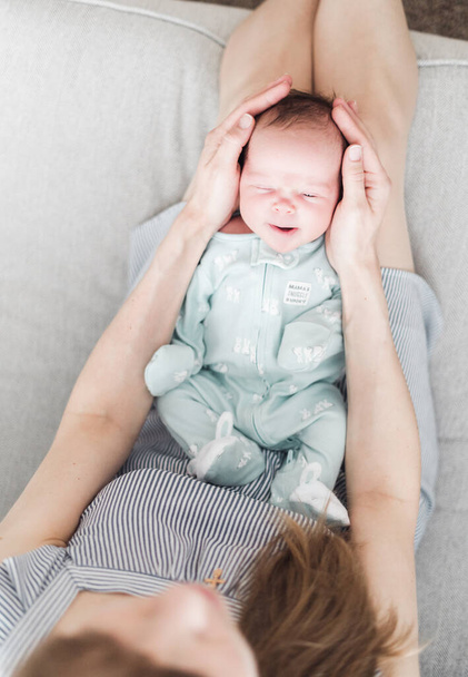Lifestyle portret van een jonge moeder en haar pasgeboren, drie weken oude dochter. - Foto, afbeelding