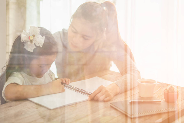 Mother helping daughter with their homework at home - Photo, Image