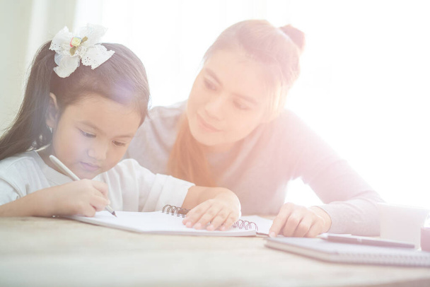 Mutter hilft Tochter bei Hausaufgaben zu Hause - Foto, Bild