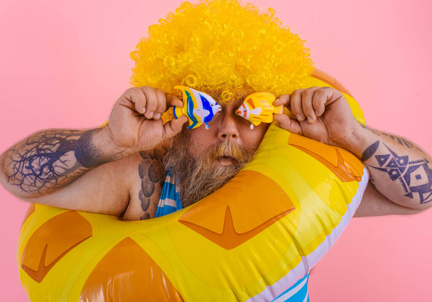 Dicker Mann mit Perücke im Kopf schwimmt mit einem Donut-Lebensretter - Foto, Bild
