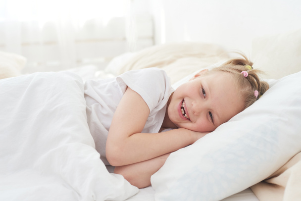 A little girl wakes up in the morning and smiles. Good dream - Foto, imagen