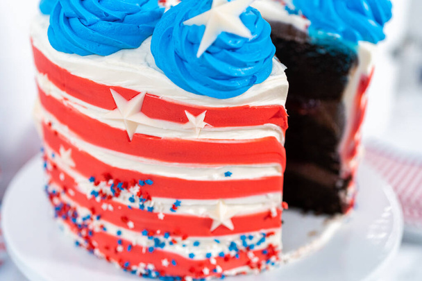 Affettare la torta di cioccolato del 4 luglio decorata con glassa al burro rossa, bianca e blu. - Foto, immagini