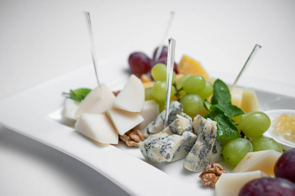 closeup of cheese plate with grape, walnuts and honey on white background - Foto, Imagen