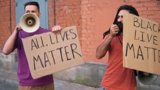 Dwóch białych mężczyzn protestuje na ulicy z megafonami i znakami - Materiał filmowy, wideo