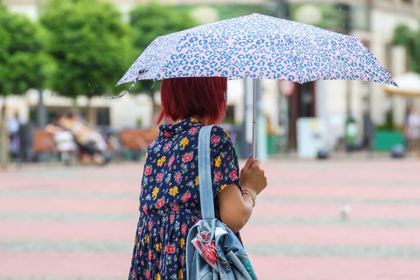 Ludzie z parasolem chodzą po ulicy w deszczowe dni. - Zdjęcie, obraz