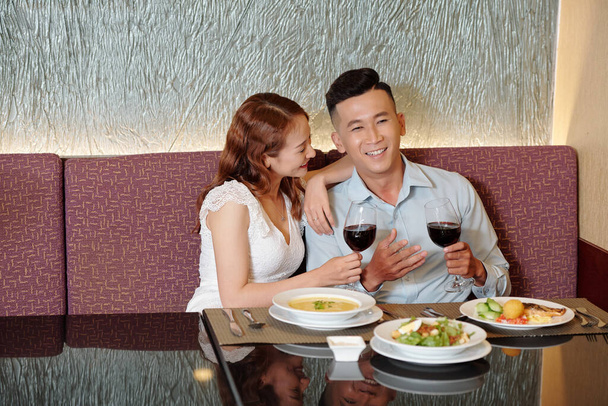 Nuori pari nauttii hyvää viiniä ja keskustelua hienossa ravintolassa - Valokuva, kuva
