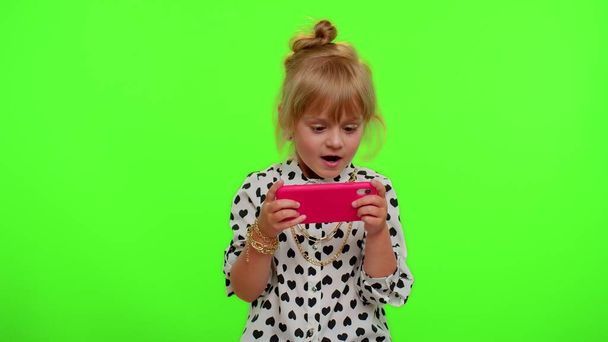Endişeli komik bağımlı çocuk kız hevesle cep telefonuyla yarış oyunları oynuyor. - Fotoğraf, Görsel