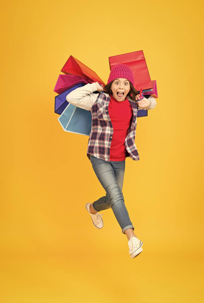 Shop for what you want. Energetic child carry shopping bags yellow background. Sale and shopping. Cyber Monday. Black Friday. Where fashion meets fun - Foto, afbeelding
