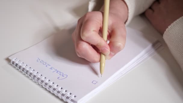 Κοντινό πλάνο των γυναικείων χεριών γράφοντας τους στόχους για το 2022 με στυλό σε χαρτί - Πλάνα, βίντεο
