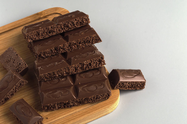 Tahta bir tahtanın üzerinde havalanmış sütlü çikolata parçaları. Boşluğu kopyala .. - Fotoğraf, Görsel