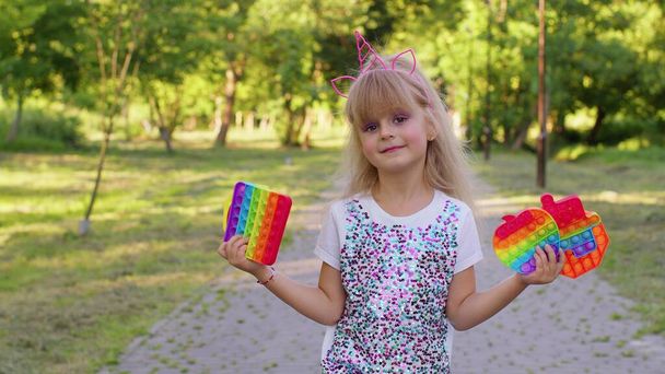 Niño niña sosteniendo muchos coloridos burbujas de silicona blanda juguete sensorial, niño jugando pop it juego - Foto, imagen