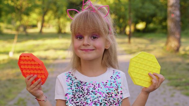 Girl holding two pop it sensory colorful anti-stress toys, squishy bubbles trendy game, anti-stress - Photo, Image
