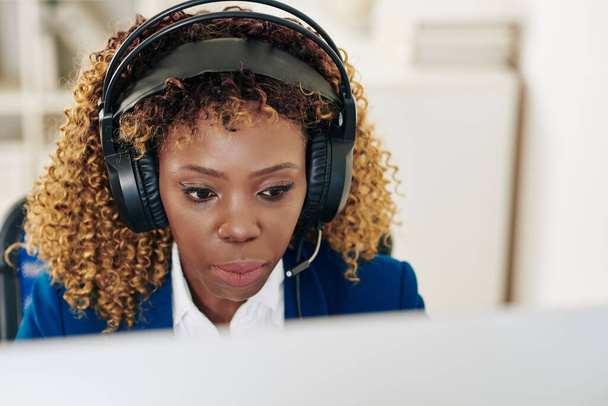 Portret poważnej kobiety obsługującej pomoc techniczną w słuchawkach pracujących na komputerze w biurze - Zdjęcie, obraz