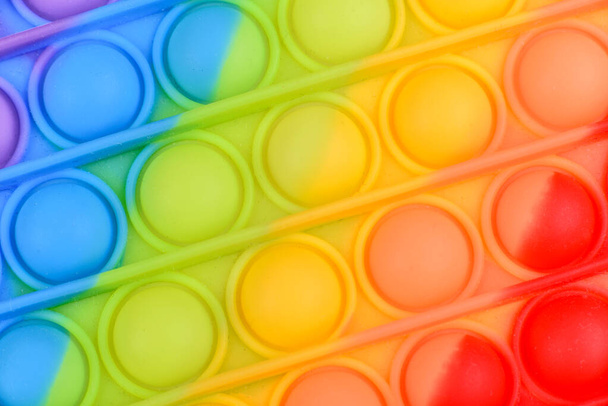 Giocattolo colorato luminoso per bambini in silicone progettato per alleviare lo stress su uno sfondo di carta da una tonnellata. Aprilo. - Foto, immagini