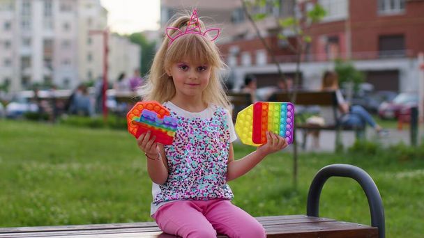 Elegante bambino bambino giocare con pop alla moda esso bolla squishy giocattolo sensoriale gioco sulla panchina del parco giochi - Foto, immagini