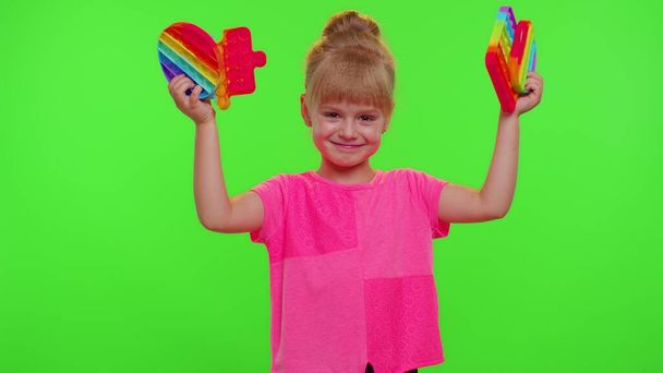 Усміхнена дитина-дівчинка тримає стискаючий антистрес поп це сенсорний екран іграшки просто димчастий гра
 - Фото, зображення