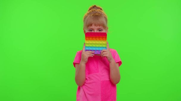 Pequeña niña apretando prensas colorido anti-estrés pantalla táctil empuje pop es juguete popular - Foto, Imagen