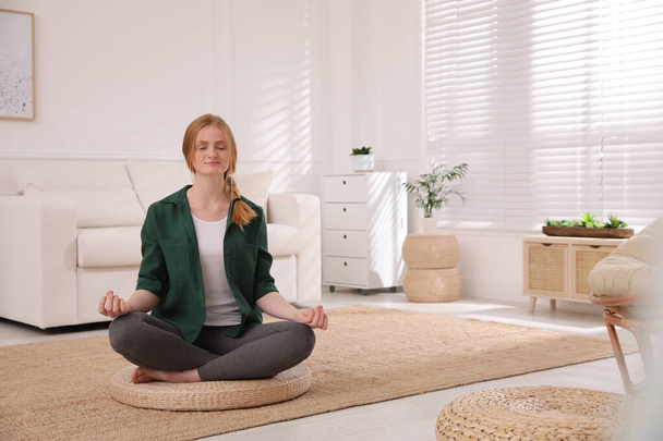 Een vrouw die thuis mediteert op een rieten mat. Ruimte voor tekst - Foto, afbeelding
