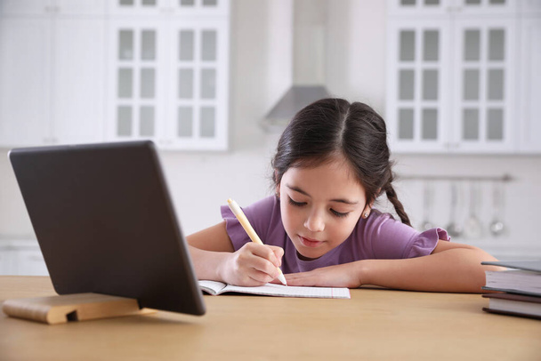 Kleines Mädchen macht zu Hause Hausaufgaben mit modernem Tablet - Foto, Bild