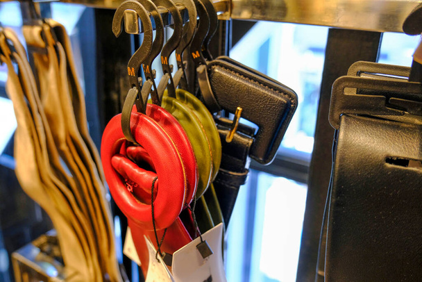 Cinturones de cuero multicolores en perchas de primer plano en la tienda de moda. Accesorios personales. Elegante atuendo - Foto, imagen